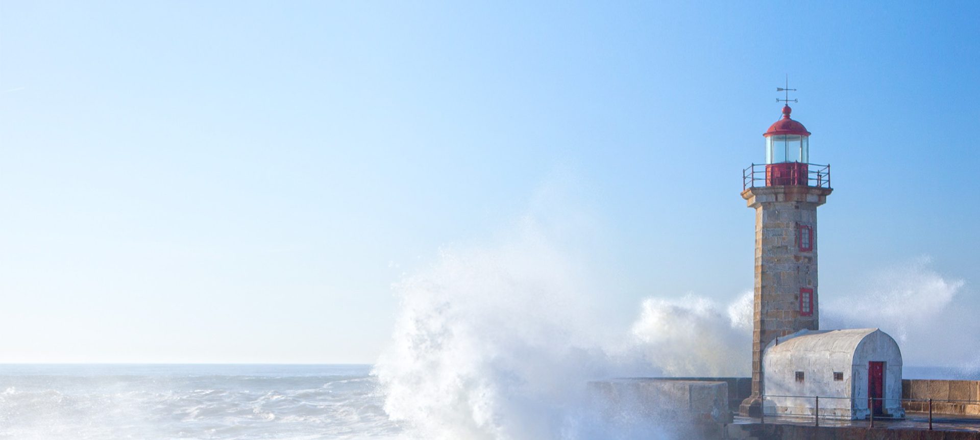 lighthouse with waves crashing behind