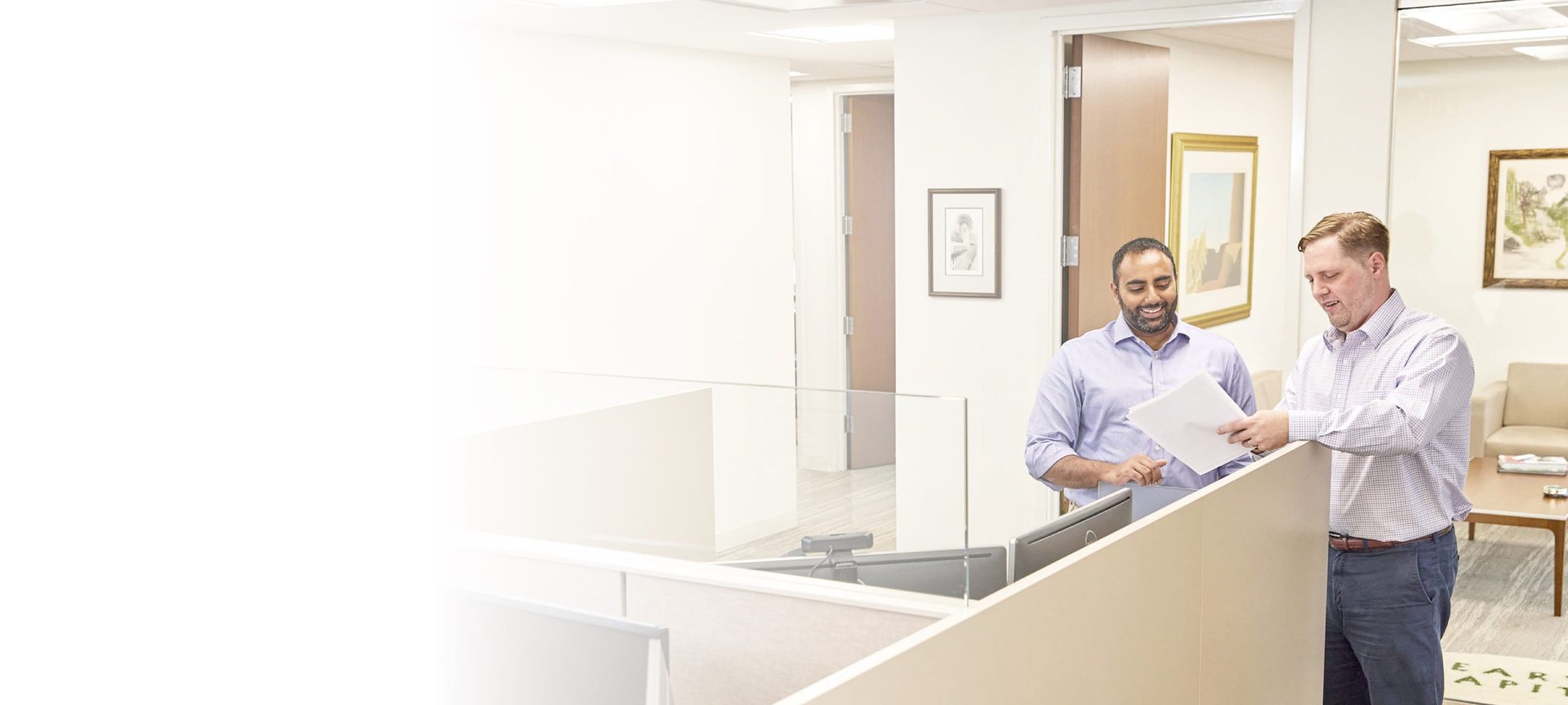 two men talking at a cubicle wall